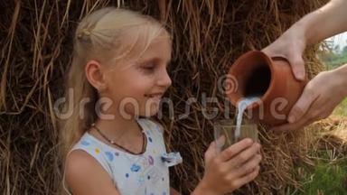 漂亮的金发女孩在农场的夏天，在干草堆上喝着一杯新<strong>鲜牛奶</strong>。